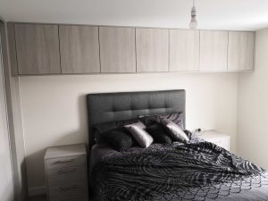 bed with cupboards above it and beside tables